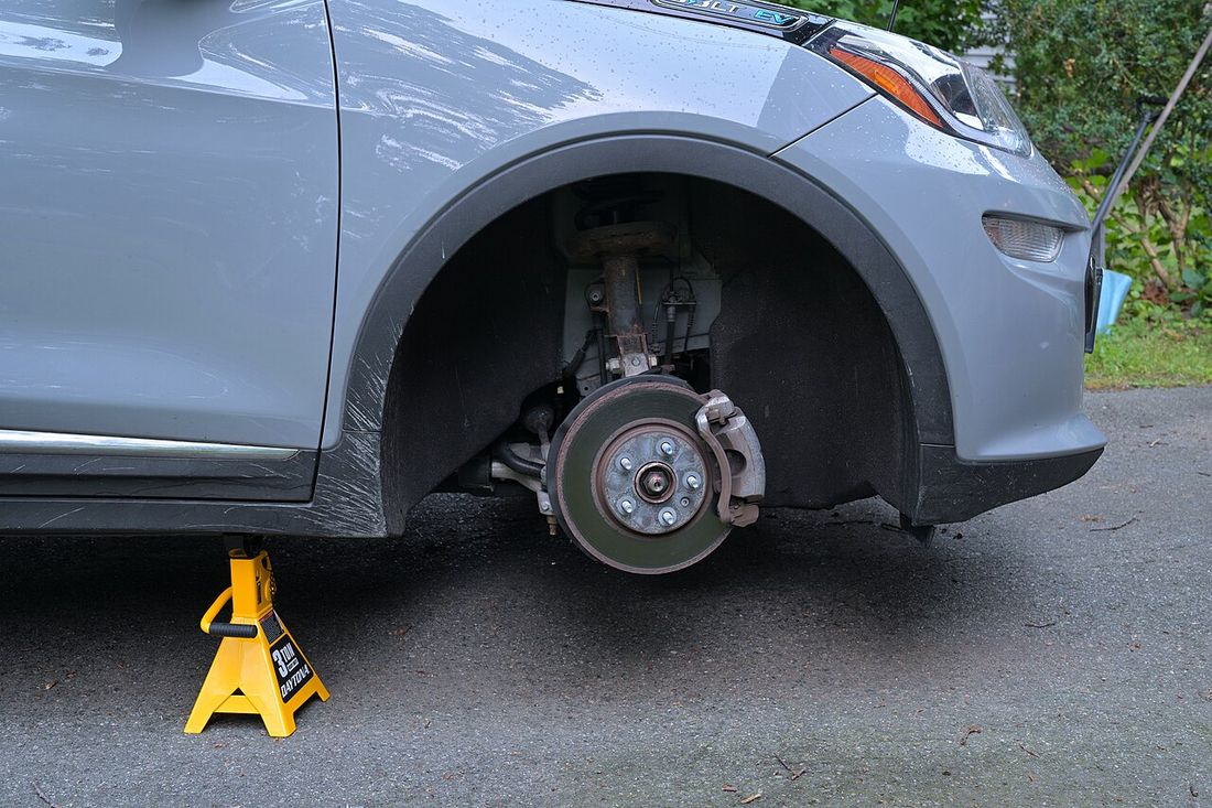 A car disc brake and caliper behind a removed wheel