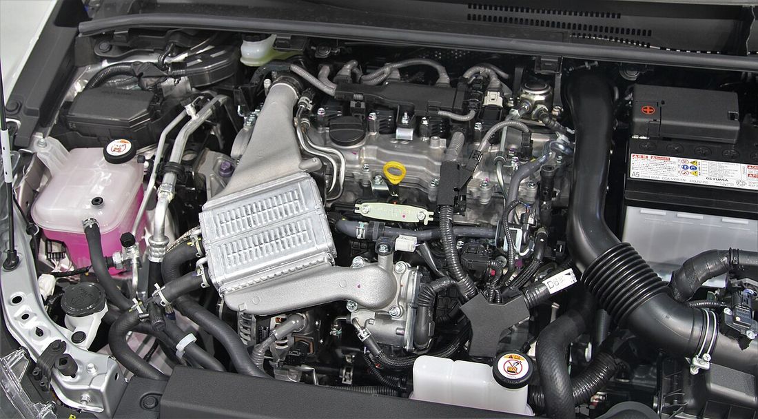 A modern petrol engine with its cover and pipework visible
