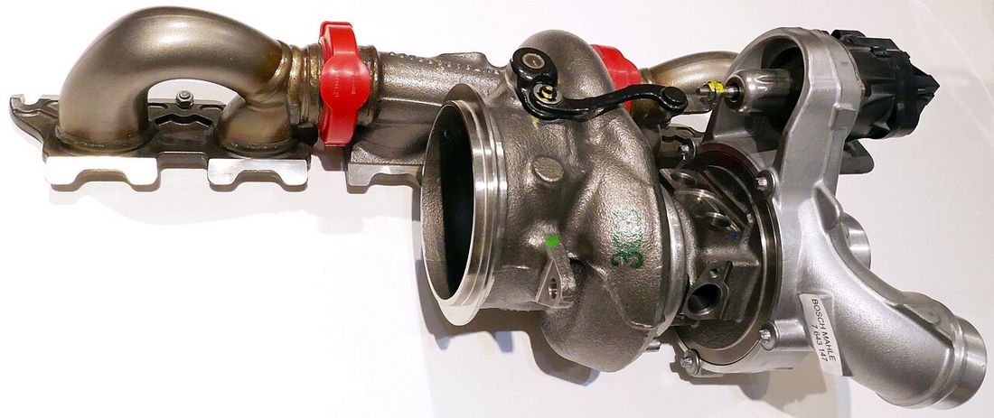 Close-up of a turbocharger showing the curved blades of its compressor wheel